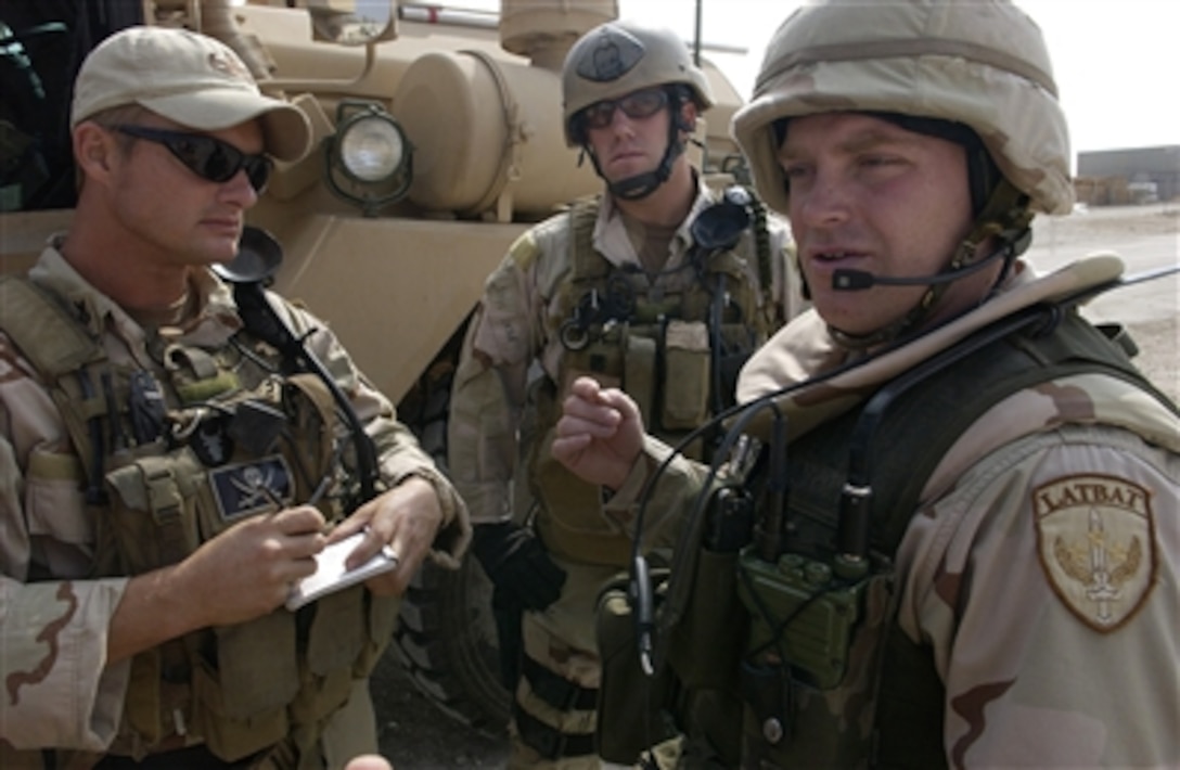 U.S. Navy Lt. A.J. Pajack, center, and Petty Officer 1st Class Travis J. Schellpeper, left, conduct a predeparture convoy brief with a Latvian army convoy commander prior to a mission into Ad Diwaniyah, Iraq, Oct. 30, 2006.