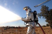 Airman 1st Class Justin Jordan, Travis firefighter, shows his ready-response by spraying water on a simulated crash site of a C-5 Galaxy during Exercise "Aircraft Down," a joint exercise between Travis Air Force Base, Calif., and the surrounding community. More than 350 people and 32 off-base agencies took part in the exercise held Oct. 19. (Travis AFB, Calif., Released)