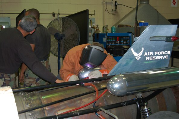 Tech. Sgt. Paul Zimmerschied, a welder with the 433rd Maintenance Group at Lackland AFB, welds the metal band around the canister of the Air Force Reserve jet car's exhaust. During Airfest 2006, two of the bands that strengthen the canister where the afterburner is ignited developed tears. With the help of the 433rd MXG metal shop, the jet car was able to continue to perform on the second day. (U.S. Air Force Photo/Master Sergeant Collen McGee)