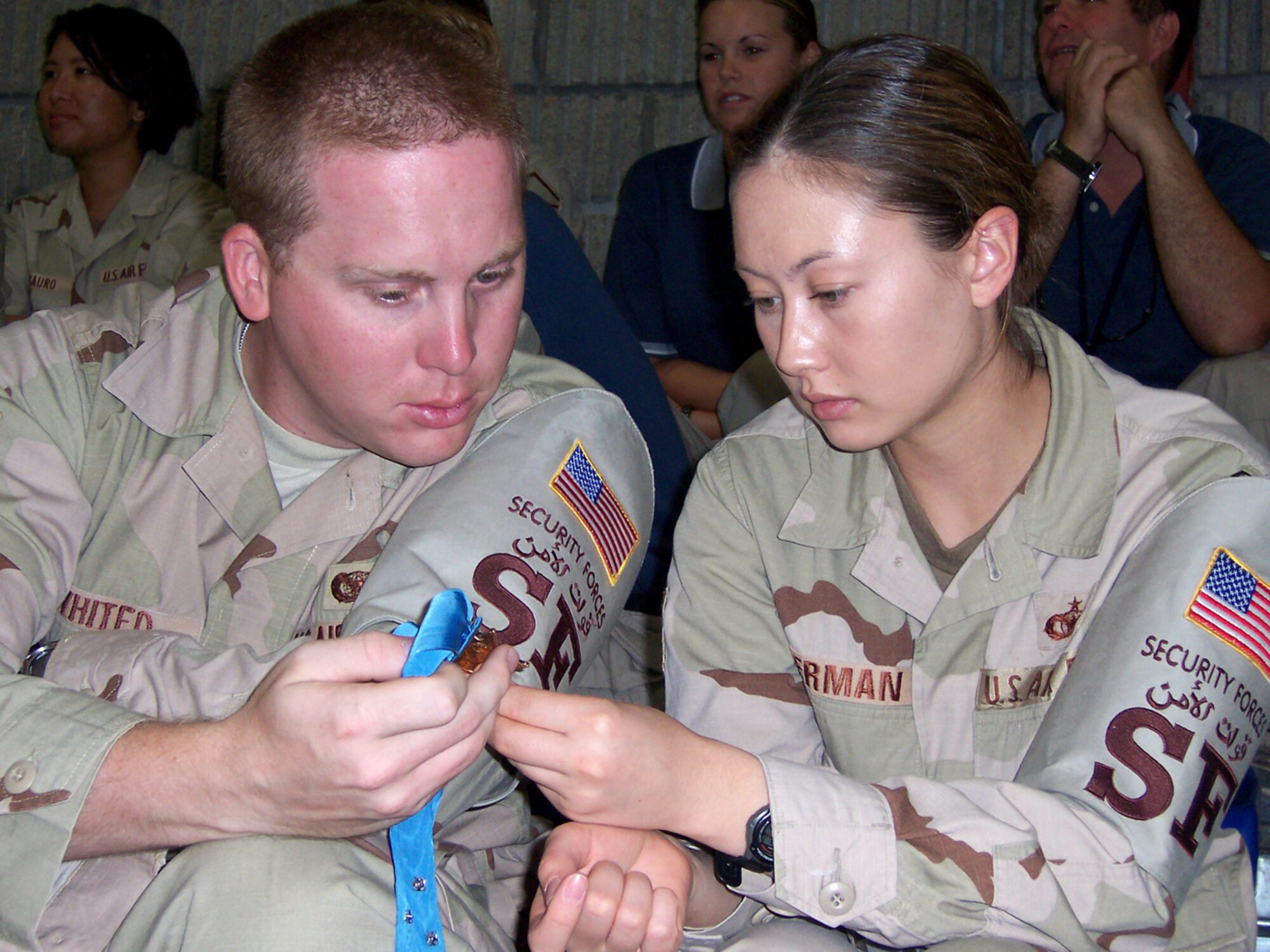379th Expeditionary Security Forces Squadron Airmen Senior Airman Justin Whited and Staff Sgt. Jennifer Sherman inspect a Medal of Honor. The two Airmen listened to Medal of Honor recipients Army Col. Robert Howard, Marine Capt. John McGinty III, and Army Command Sgt. Maj. Gary Littrell, all retired, share their messages of hope and patriotism at an assembly Nov. 3 at a base in Southwest Asia. (U.S. Air Force photo/Tech. Sgt. Steve Staedler)