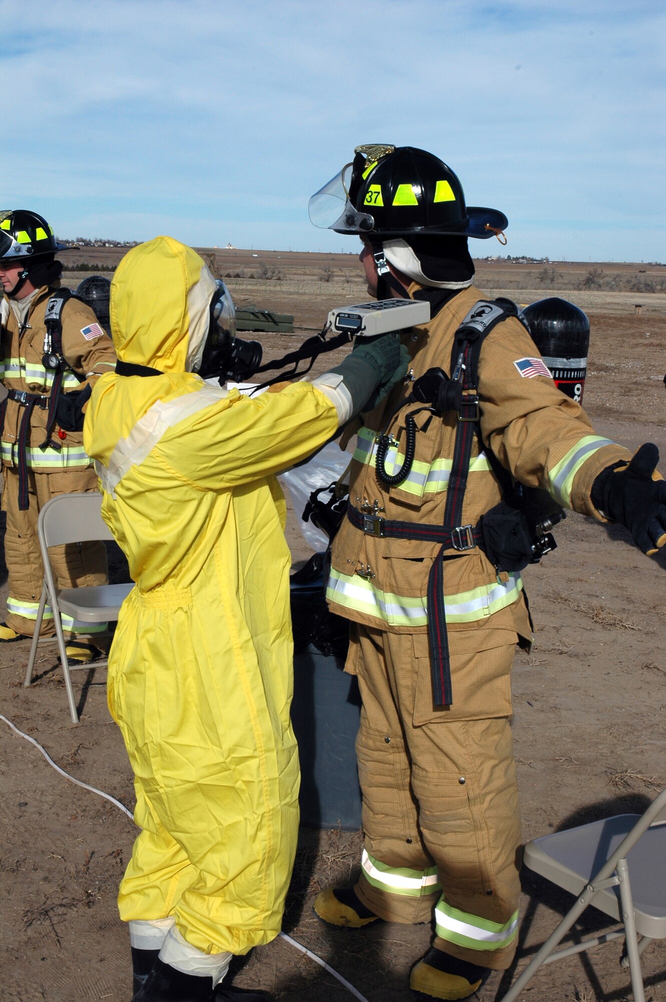 BUCKLEY AIR FORCE BASE, Colo. -- Airman 1st Class R.J. Cockrell, 460th Civil Engineer Squadron Emergency Management Flight, checks the fire suit of Mr. Chris DeBaca, 460th CES Fire Protection Flight, for alpha radiation at the decontamination point during an exercise here Nov. 7. Members of the 460th Civil Engineer Squadron Emergency Management Flight, 460th Medical Group Bioenvironmental Flight and 460th CES Fire Protection Flight exercised their ability to move people from a contaminated area into an uncontaminated area through a decontamination line. (U.S. Air Force photo by Staff Sgt. Sanjay Allen)