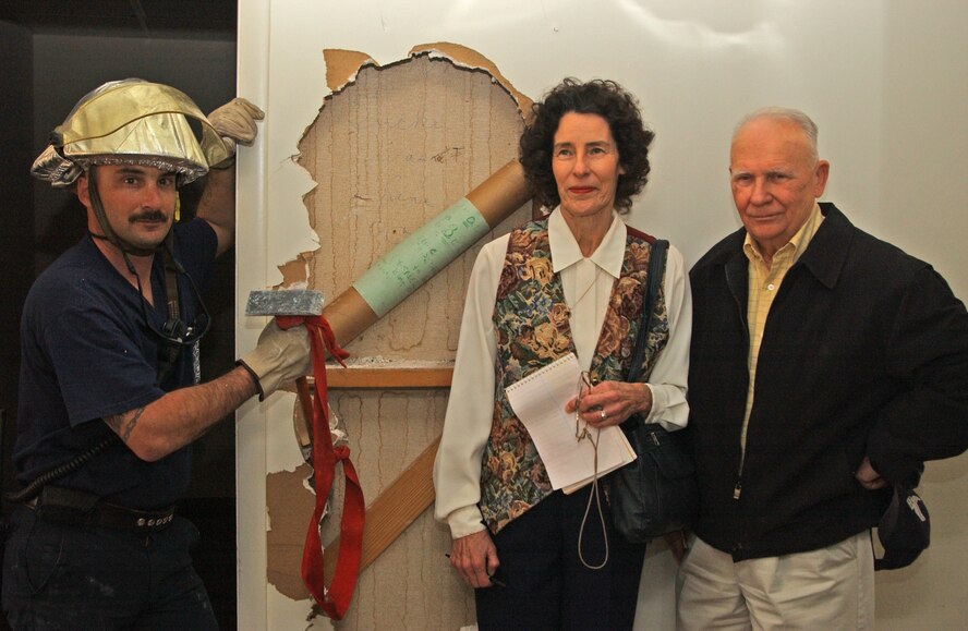 Dave Schacher, Vance Fire Department fireman, opens a wall in Bldg. 600 to locate a 1977 time capsule for Judy Ecker. Ms. Ecker was a Team Vance member for more than 40 years.(Photo by Frank McIntyre)