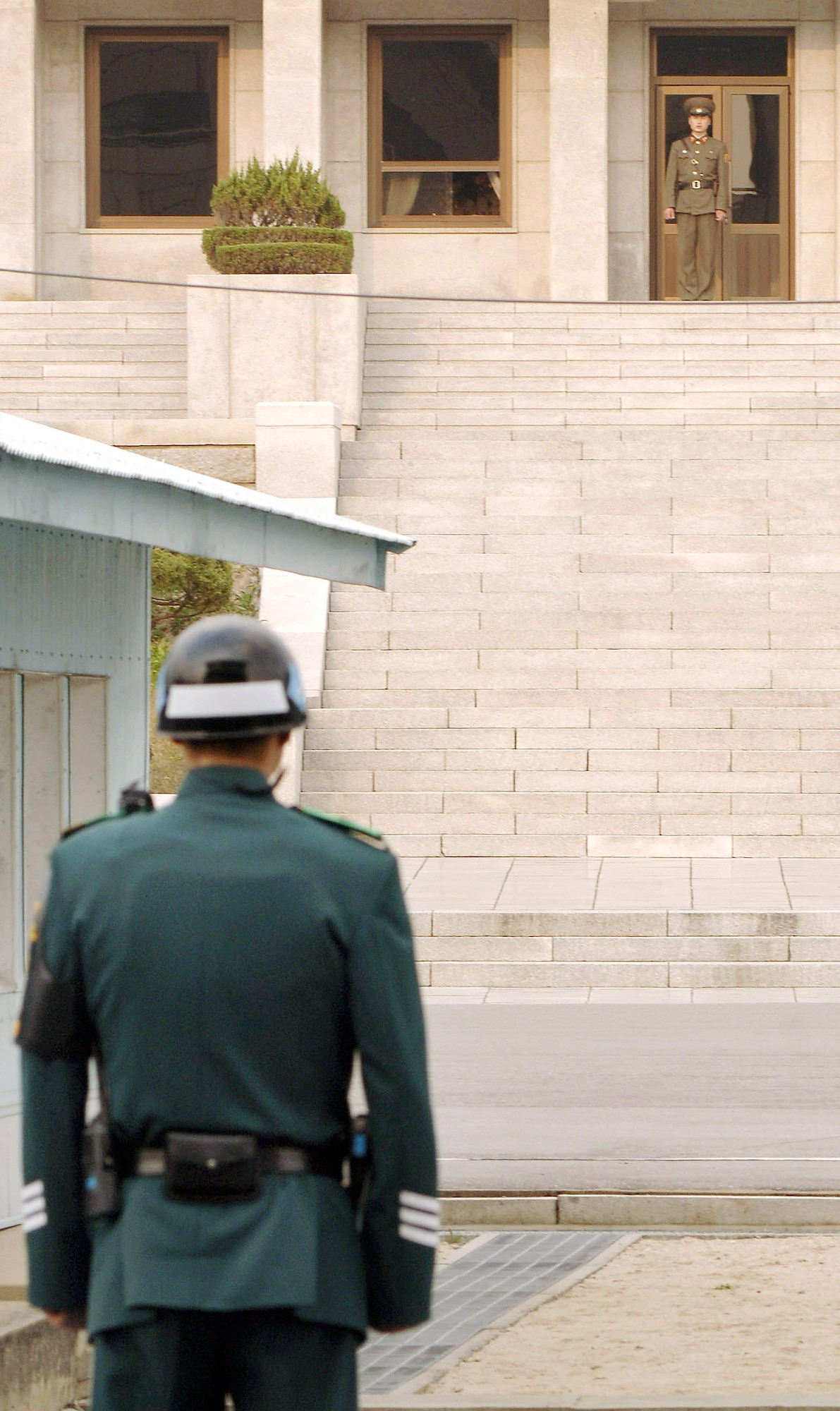 A Republic of South Korea soldier stands in a face-off with his North Korean counterpart on the steps of the Panmun-guk building that separates the two countries. (U.S. Air Force photo/Daren Reehl) 
