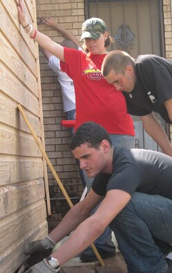 Despite steady rainfall April 28 and Saturday morning, 60 non-prior service Airmen and active duty members from the 362nd Training Squadron stood ready to assist the annual area Christmas in Action program.  Above, house captain Airman Jason Winnick, works on the siding of a home as Airmen Christopher Hood and Erin Carrier get ready to help with flashing. Weather didn’t pose much of a deterrent as half the crew went out to work on two Wichita Falls homes on Elm and California streets.  Prepared for construction, electrical and yard work duties, the group was able to finish some siding and landscaping chores and will return next weekend to complete the exterior paint job. (U.S. Air Force photo/Debi Smith).