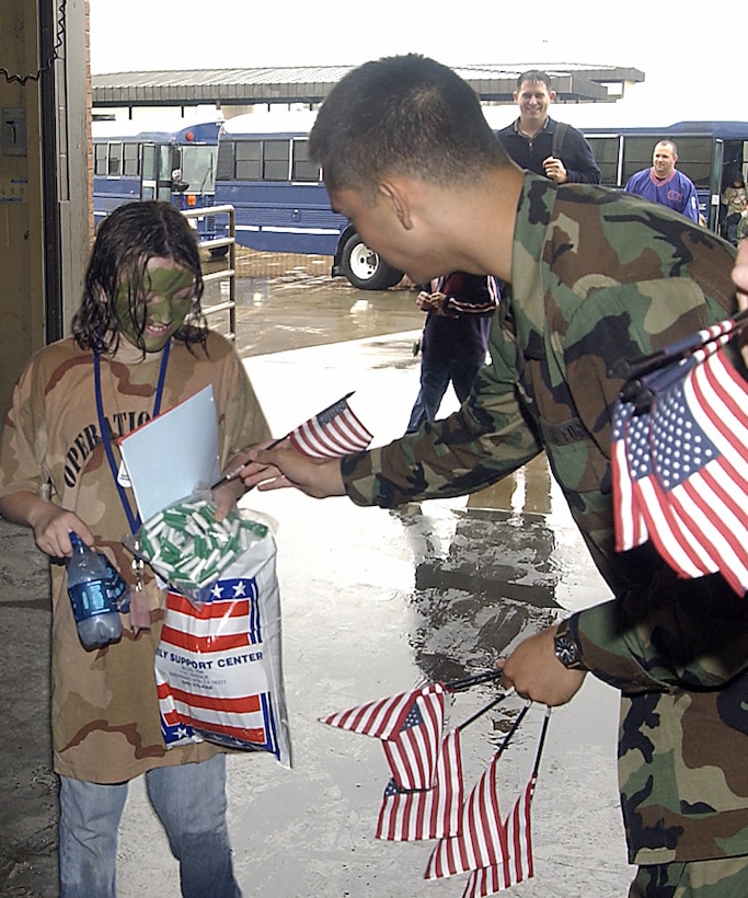 A Team Sheppard member welcomes home a participant in Saturday’s Operation Kids 2006 after a “lenghty deployment” to Camp Liberty. About 150 children of Team Sheppard personnel braved the weather, processing lines, briefings and MREs to experience what takes place when preparing for a deployment. (U.S. Air Force photo/Mike Litteken).