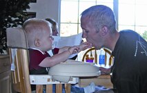 One year-old Tyler McClure demonstrates his technique for feeding his instructor pilot dad, 1st Lt. Philip McClure while mom Valerie reads the newspaper. Lieutenant McClure said balancing family time with his duty schedule is difficult but possible with the support of an understanding family and efficient time management. (Photo by Capt Tony Wickman)
