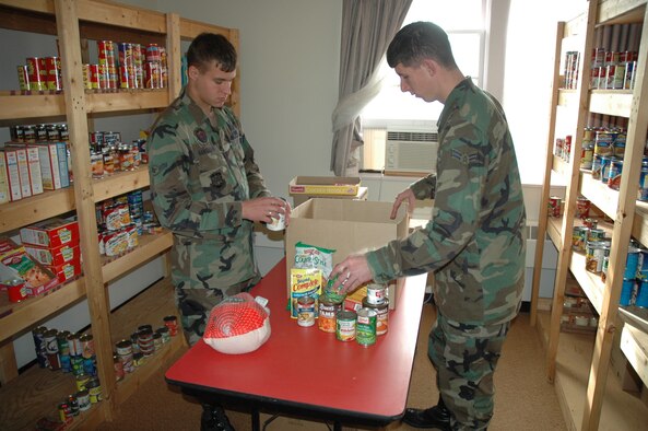 Airman Michael Hanselman (left),  and Airman 1st Class Benjamin Lee (right), both 791st Missile Security Forces Squadron, put together Thanksgiving Day baskets at the First Sergeant’s Food Pantry Tuesday. The baskets include a complete Thanksgiving Day dinner and will be distributed by the First Sergeants Nov. 17. (U.S. Air Force photo by Airman Wesley Wright)