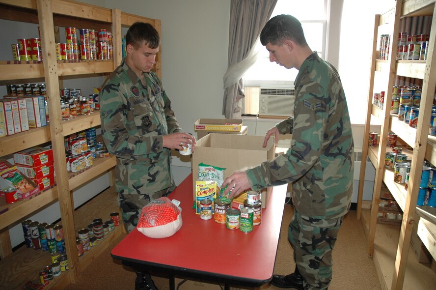 Airman Michael Hanselman (left),  and Airman 1st Class Benjamin Lee (right), both 791st Missile Security Forces Squadron, put together Thanksgiving Day baskets at the First Sergeant’s Food Pantry Tuesday. The baskets include a complete Thanksgiving Day dinner and will be distributed by the First Sergeants Nov. 17. (U.S. Air Force photo by Airman Wesley Wright)