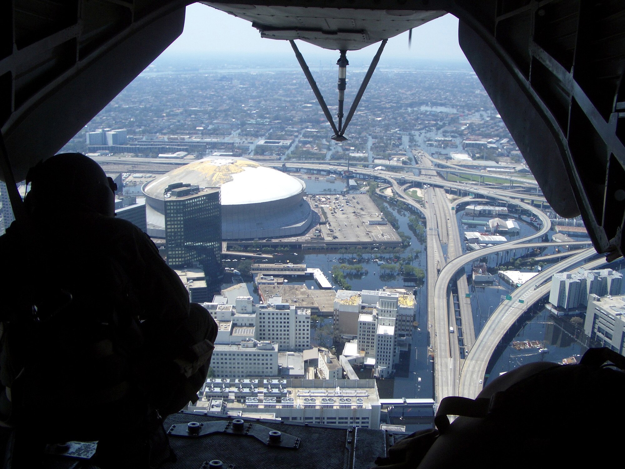 A 20th Special Operations Squadron MH-53 PAVE LOW gunner looks out over the submerged aftermath surrounding the New Orleans Superdome during a Hurricane Katrina relief flight. (Courtesy Photograph)

