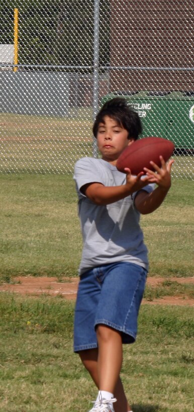 Ryan Stevens catches the ball during a flag football game at the youth centers summer sports camp. (U.S. Air Force photo/Amn Jacob Corbin).