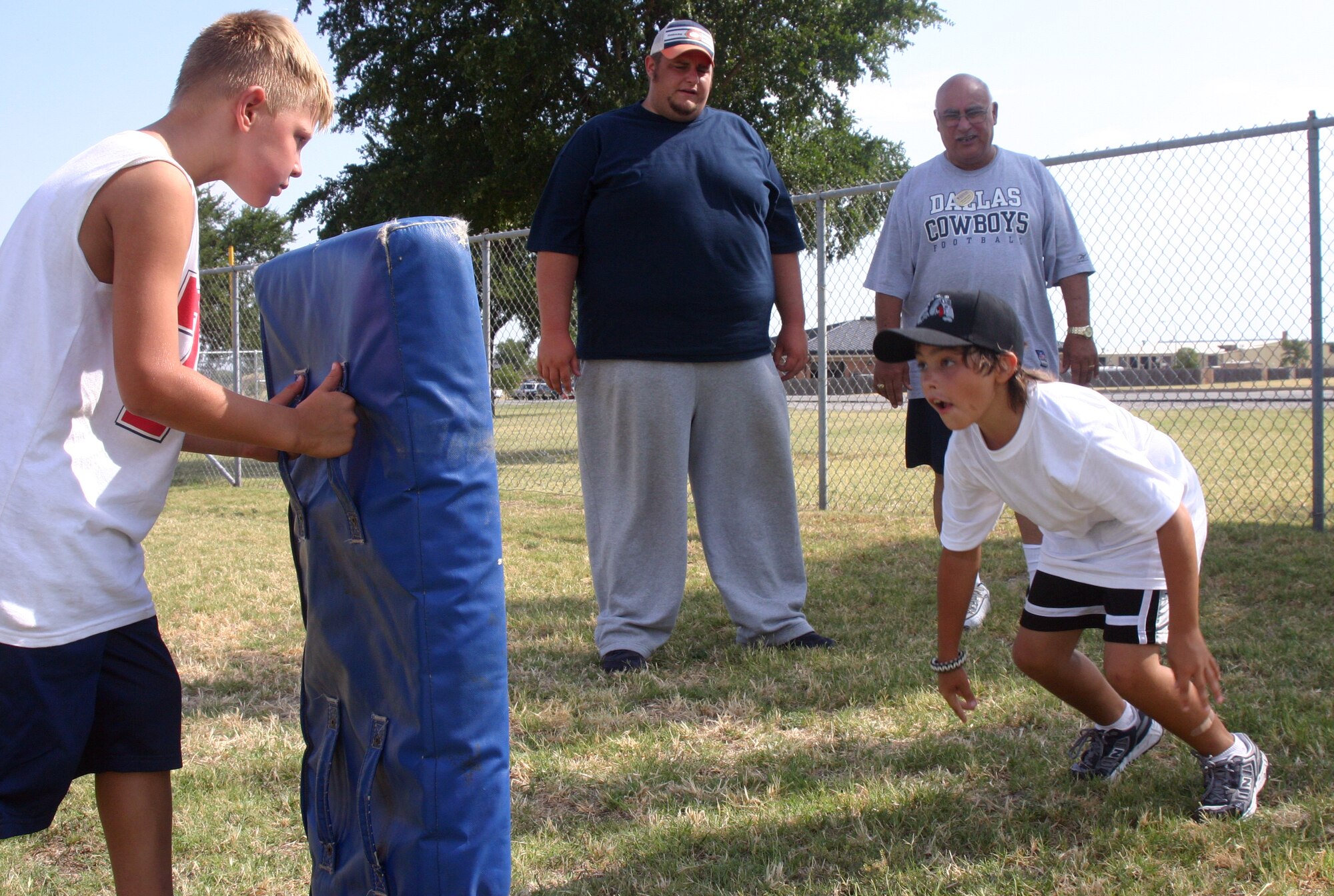 Ty Crouse holds up a blocking pad at the youth center’s summer sports camp for fellow camp attendee Tristan Spiva Monday. (U.S. Air Force photo/Amn. Jacob Corbin).