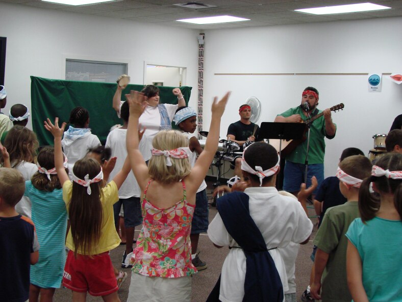 Vacation Bible School band members lead VBS participants in worship songs during music lessons. The children, ranging from preschoolers to those entering sixth grade, participated in music, snacks, crafts, lesson time and a “village playground.” (Photo by Staff Sgt. Amanda Savannah)