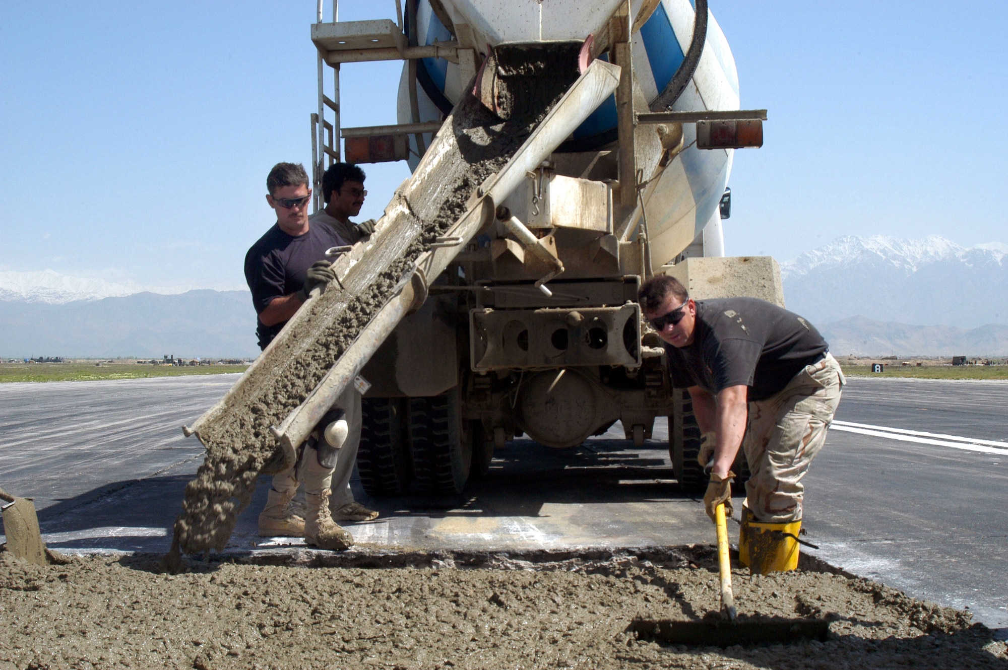 Tech. Sgt. John Foster (left) pours concrete on the active runway at Bagram Air Base, Afghanistan, as part of a $2.3 million airfield repair project. Tech. Sgt. James Holman spreads concrete in a hole. The runway project was one handled by Robert Owens, a civilian with the Tulsa Branch of the Army Corps of Engineers here. (U.S. Air Force photo/Tech. Sgt. Adam Johnston).