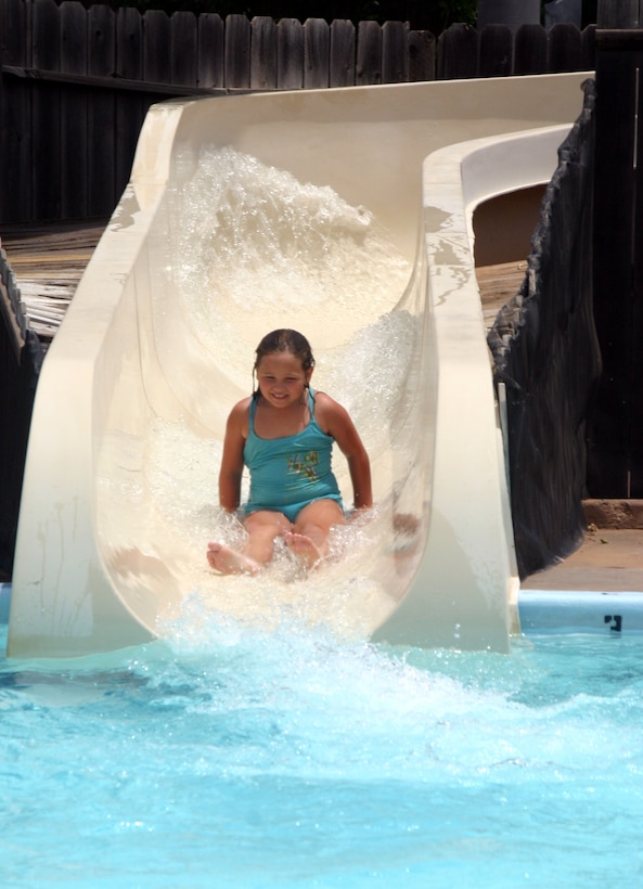 Eight-year-old Bridgette Collins races down a water slide at the Bunker Hill pool Monday. To ride the water slide alone, participants must pass a swim test to ensure safety. (U.S. Air Force photo/Airman Jacob Corbin).