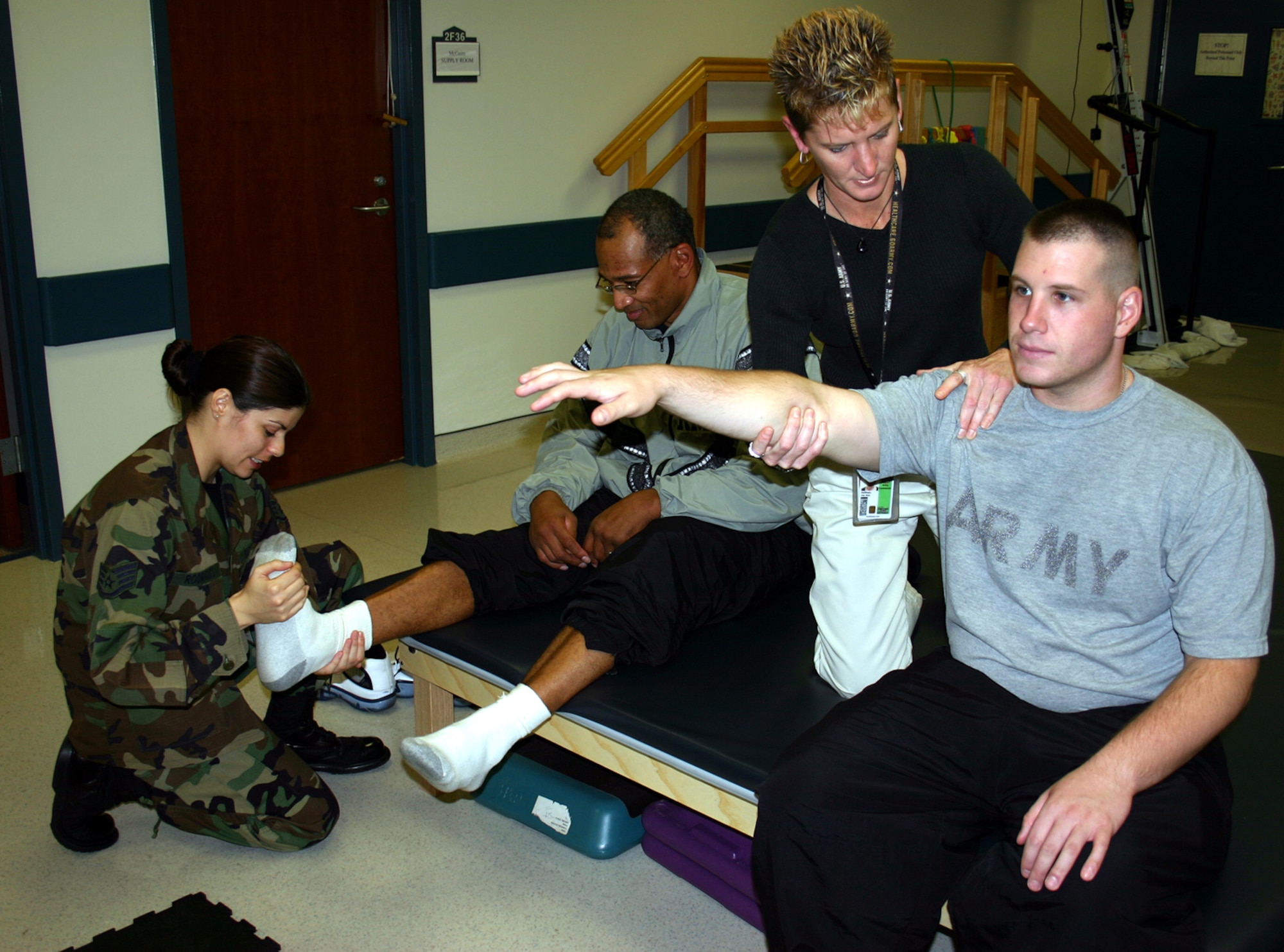 Staff Sgt. Lucinda Rodrigues (far left), 305th MDG physical therapy technician, assists Army Reserve Maj. Mercer Hedgeman, while Joy Hoffman (right), Army Joint Readiness Center physical therapy assistant, works with Army Sgt. Steve Harris, at the 305th MDG physical therapy department Wednesday. The Air Force and Army are currently collocated in the medical clinic here and are working toward providing joint services as McGuire and Fort Dix merge support functions. 