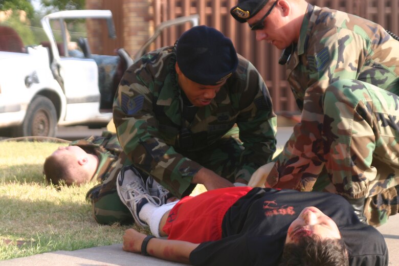 82nd Security Forces Squadron members Tech. Sgt. Michael Jones and Staff Sgt. Joseph Hobert provide self-aid and buddy care during an exercise Wednesday near the community center. (U.S. Air Force photo/John Ingle)