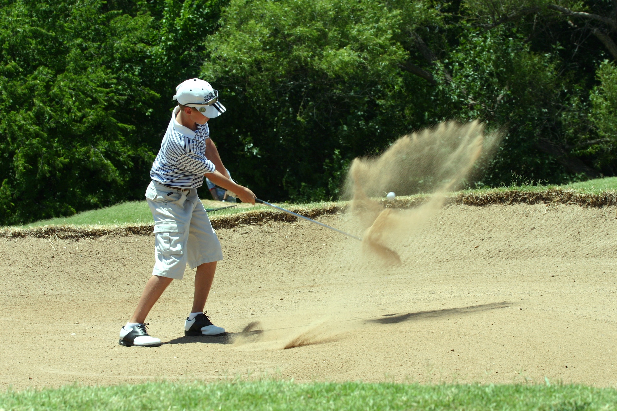 Taylor Schoppa, 12 years old, pitches out of a sand trap during the Texas-Oklahoma Junior Golf Tournament at Wind Creek Golf Course Monday. Schoppa said he came out to the tournament to see how he would play against other competitors.  (U.S. Air Force photo/Airman Jacob Corbin).