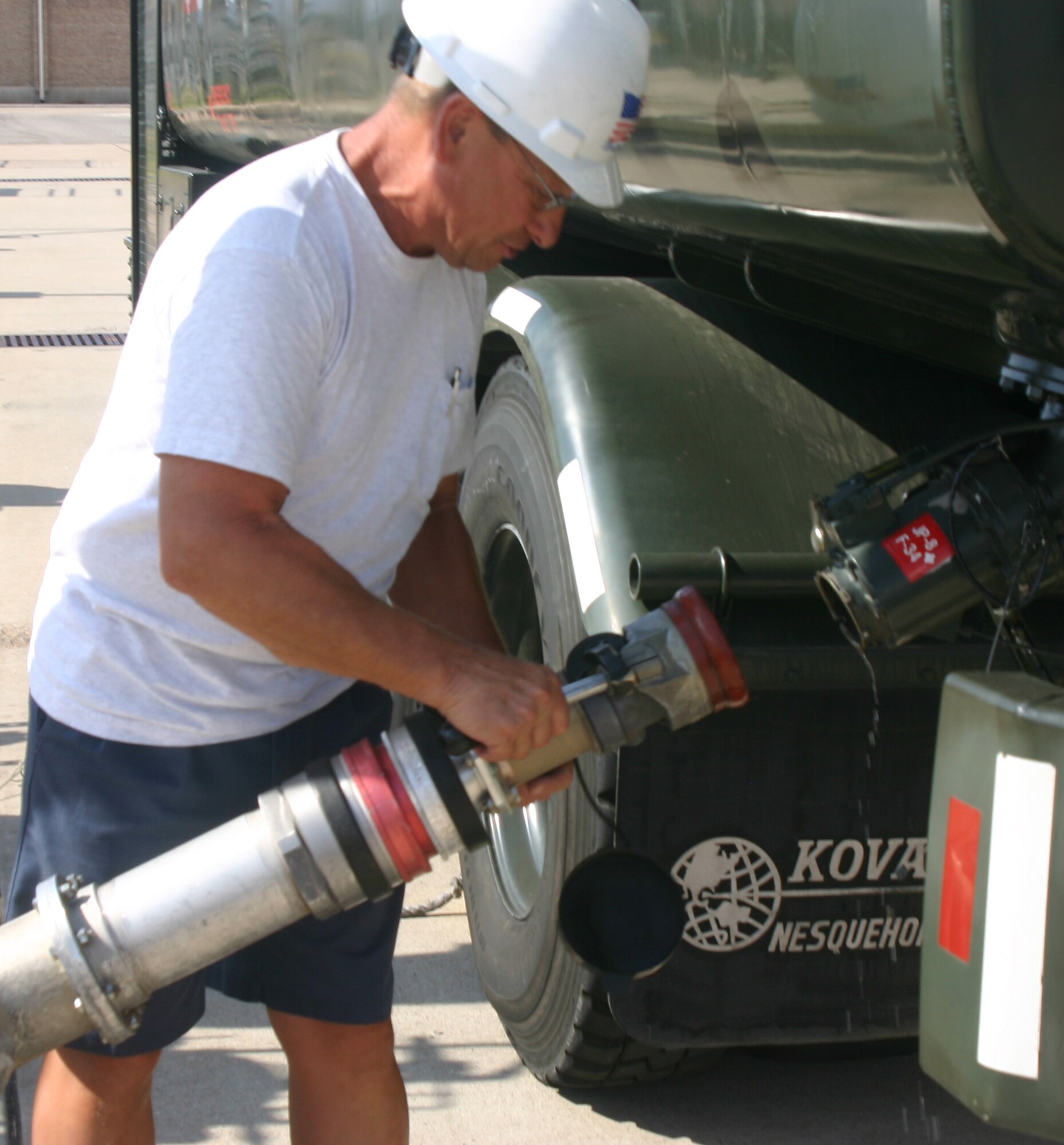 Richard Childers, a refuel driver, hooks up a fuel hose to his truck. (U.S. Air Force photo/Robert Fox)