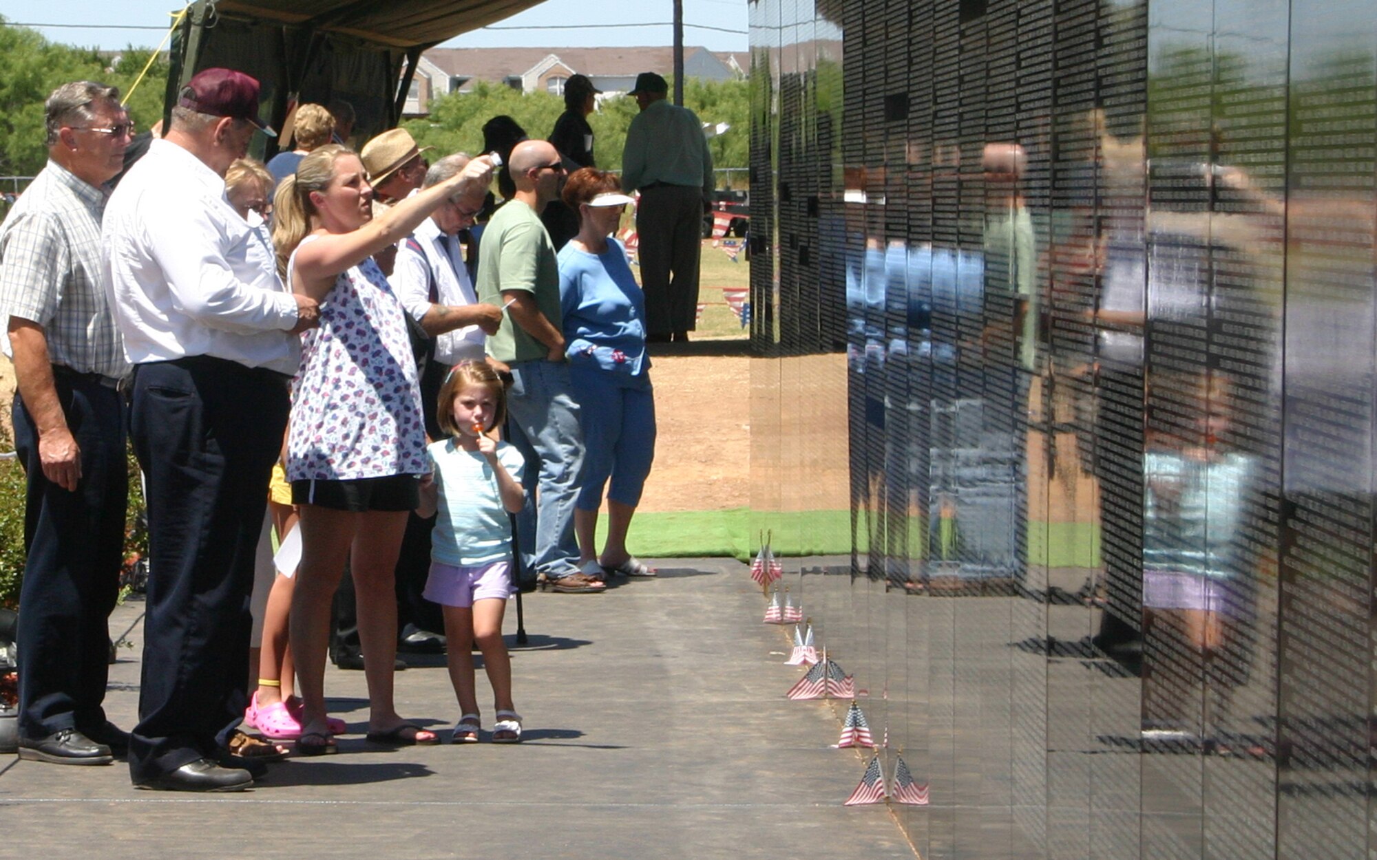 Images of the present merge with those of the past as a family visits the Vietnam Moving Wall Sunday at Crestview Memorial Park in Wichita Falls. The wall is a replica of the Vietnam Veterans Memorial in Washington, D.C. Drivers take the wall around the country to remind those of the lives lost during the Vietnam War. (U.S. Air Force photo/Senior Airman Tonnette Thompson).