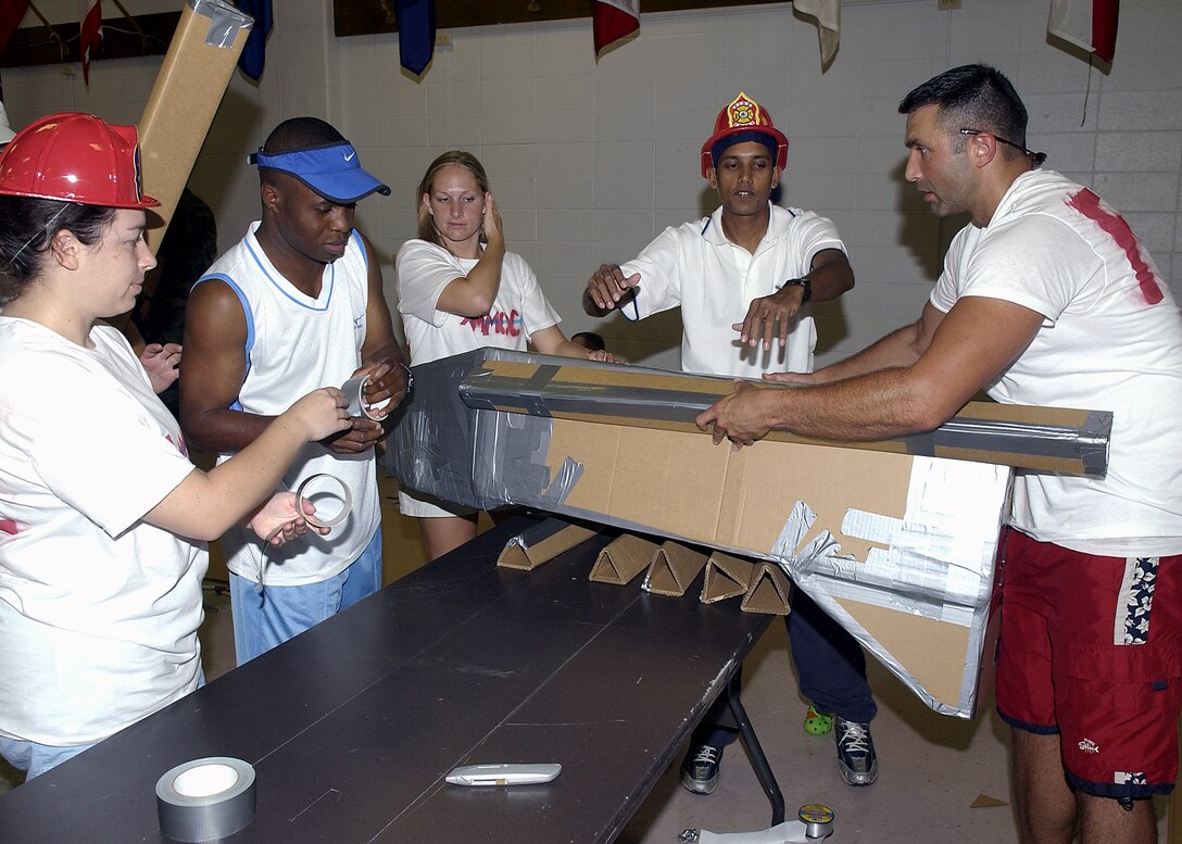 Members of the 360th Training Squadron, team number two, at the boat race Saturday work together to consturct their entry for the event. Teams had only duct tape and five sheets of cardboard to build their teams vessels. (U.S. Air Force photo/Mike Litteken).