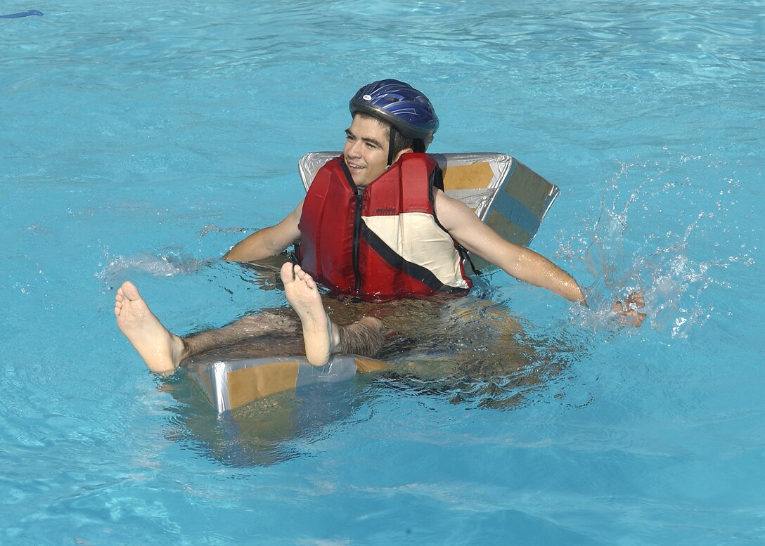 A participant in the cardboard boat race Saturday attempts to maneuver a quickly sinking entry to the end of the pool and back. (U.S. Air Force photo/Mike Litteken).