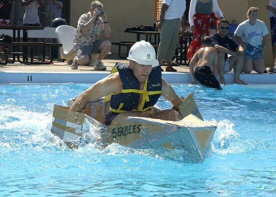 Steve Legg propels the Nave Seabee team cardboard boat across the main pool at the cardboard boat race Saturday. The Seabees duct-taped paddles they built from spare boat-making materials to his hands, eschewing the standard canoe paddle given to all the teams. (U.S. Air Force photo/Mike Litteken).