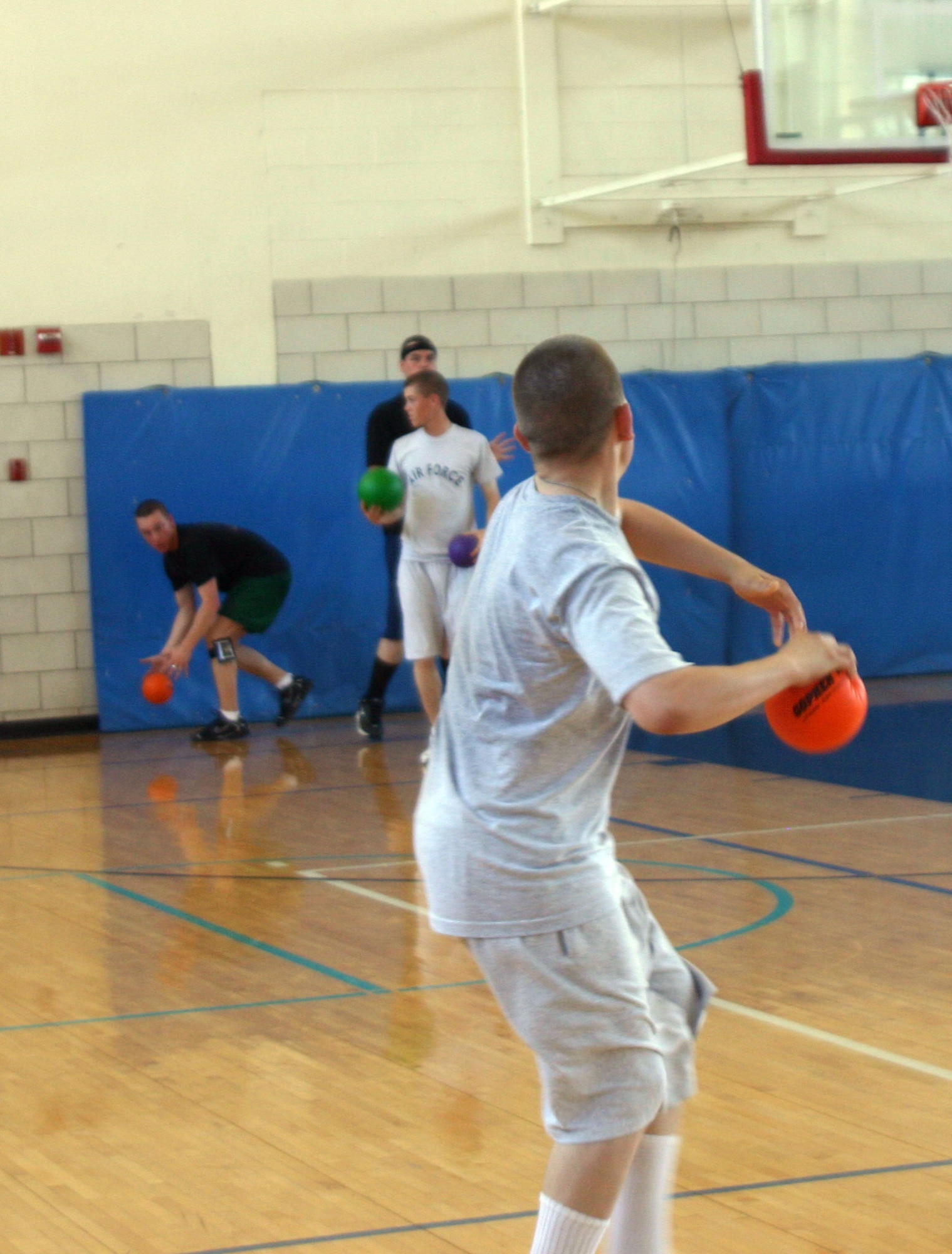 An Airman participating in the FITS program takes aim and winds up to throw as his opponent scrambles to grab a ball with which to retaliate. (U.S. Air Force photo/Airman Jacob Corbin).