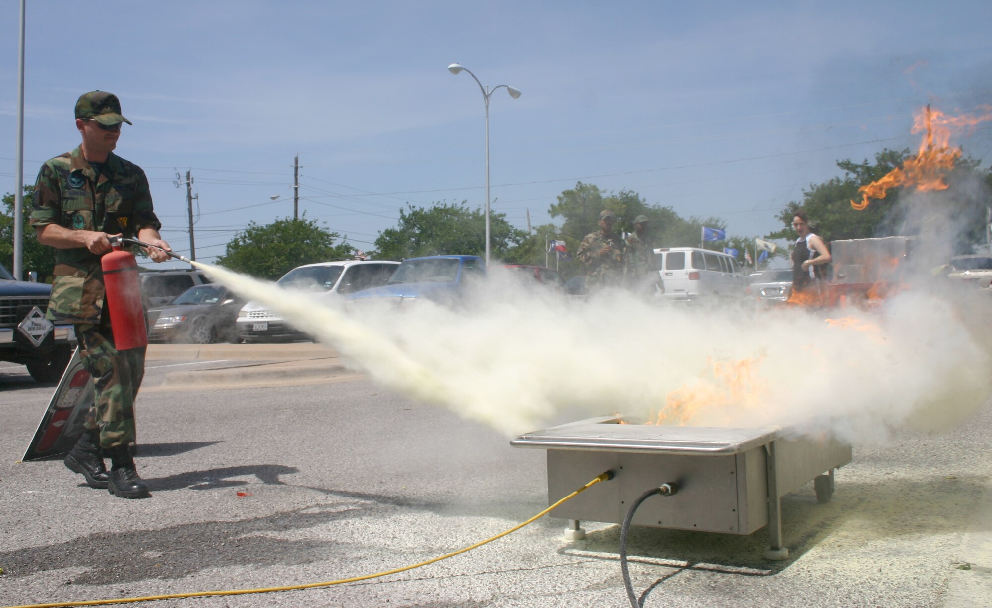 Staff Sgt. Jonathan Murkins, from the 360th Training Squadron, puts out a controlled fire with a fire extinguisher as part of the Sheppard Fire Department’s display and briefing during the Safety Day Fair May 26. Members of the fire department trained spectators on how, where and when to use different types of extinguishers. (U.S. Air Force photo/Senior Airman Jacque Lickteig).