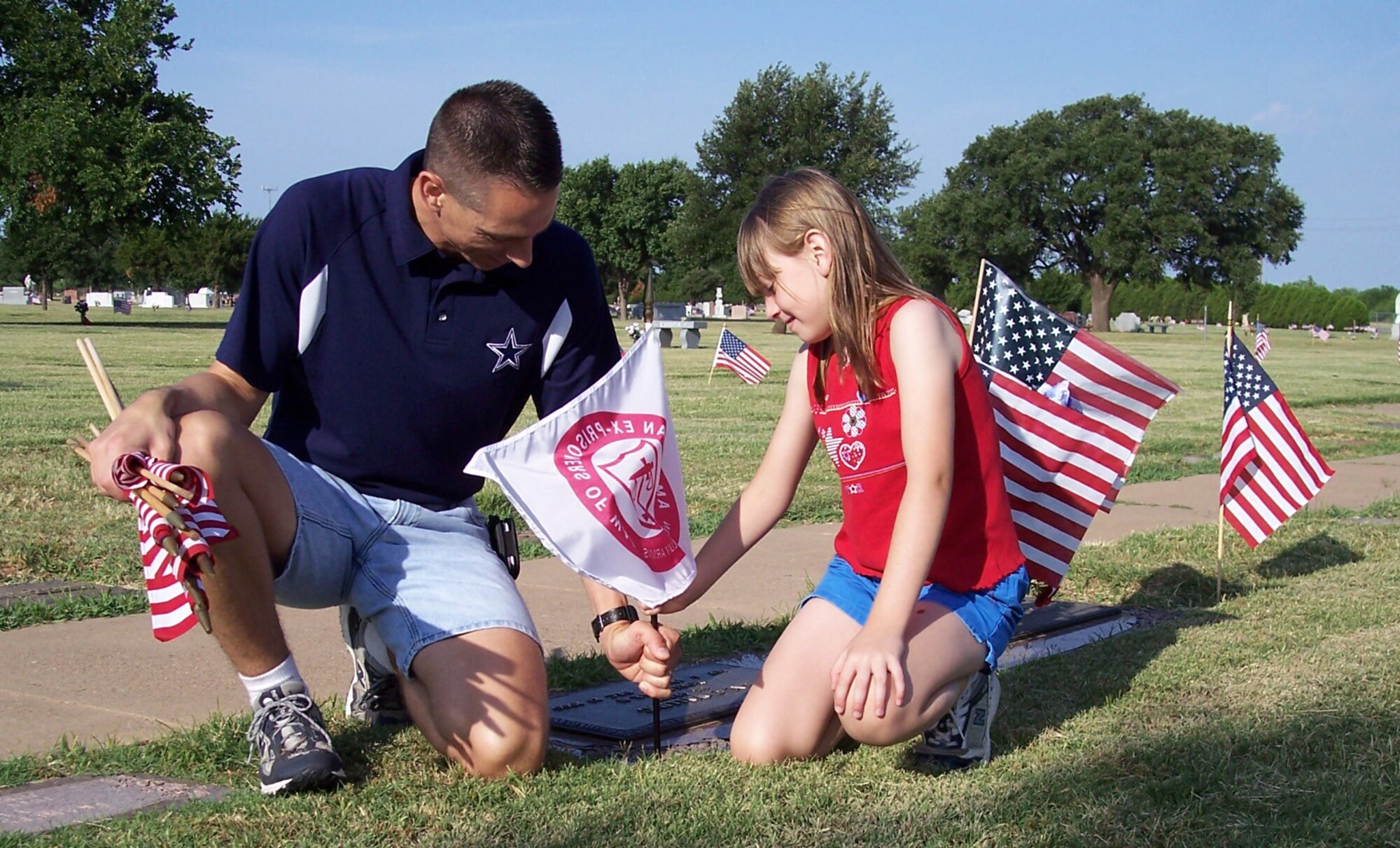 Local Chapter 1054, Air Force Sergeants Association and Sheppard personnel took part in placing American flags on the grave sites of veterans. In this particular photo, AFSA helped place 25 American Ex-Prisoners of War flags.  Master Sgt. Kenneth Boteler, an AFSA member assigned to the 361st Training Squadron, and his daughter are placing one of the 25 American Ex-Prisoners of War flags. The groups place more than 3,000 American flags and 25 American Ex-Prisoners of War Flags. (U.S. Air Force photo).