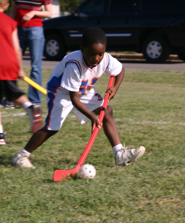 Damante Cross, a first-grade student at Sheppard Elementary, guides the ball during the field hockey race Friday.  (U.S. Air Force photo/Airman Jacob Corbin).