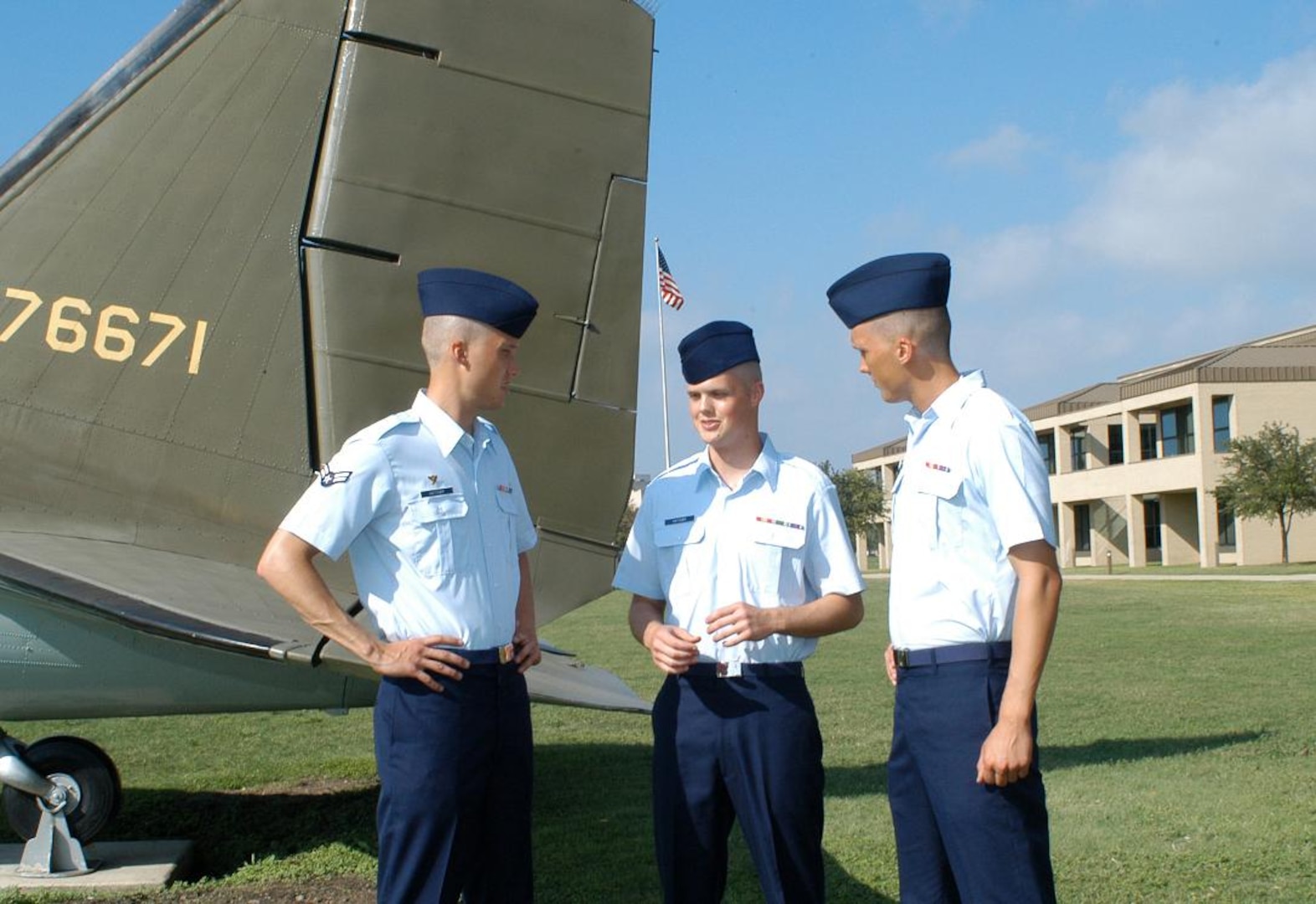 The Hatcher brothers, left to right, Airman First Class Logan and Airmen Basic Derek and Chaz, discuss their experiences during basic training near a C-47 aircraft display on Lackland Air Force Base's parade field.  The three brothers all joined the Air Force from Fort Worth, Texas, and graduated Nov. 10. (U.S. Air Force photos/Alan Boedeker)