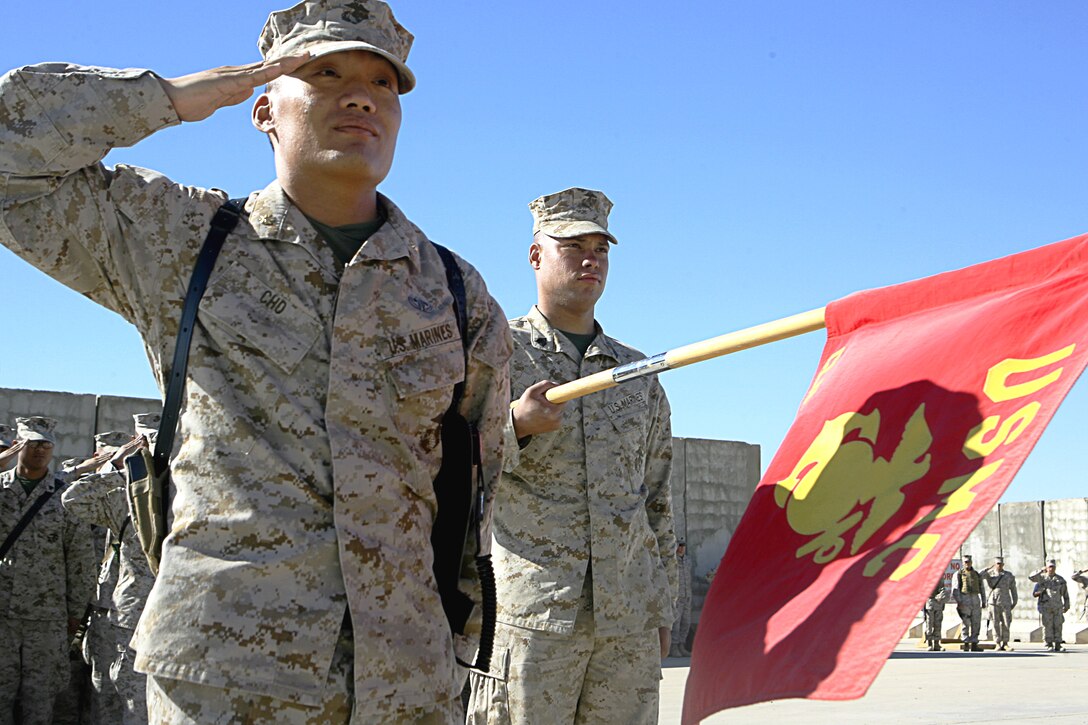 Major Michael M. Cho, 35 of Burke, Va. and commander of Communications Company, Combat Logistics Regiment 15, 1st Marine Logistics Group (Forward) salutes and Sgt. Christian R. Lebron, 24 of Queens, N.Y. and an electrician with Communications Company holds a flag as the color guard posts during the ceremony. On November, 10, 2006, Marines from Camp Taqaddum stood together to hear Lejeune?s birthday message and celebrate the Marine Corps? 231st year.  Col. David M. Richtsmeier, commander of 1st MLG (Forward), urged the audience to remember how Marines have stood together, in every clime and place, for 231 years.  ?Just as those who have come before us, the sense of honor, courage, commitment, and patriotism is etched into the souls of all Marines in our ranks today,? said Richtsmeier, a 51-year-old native of Waterloo, Iowa.  Many Marines said they felt a strong sense of pride during the ceremony.  Others became nostalgic after hearing General LeJuene?s message.  ?It takes you back to square one, when you (first) got that (Eagle, Globe and Anchor) in your hand,? said Sgt. Raymond A. Cezair, 27 from Brooklyn, N.Y., and a cook with Headquarters and Service Company, CLR-15.
