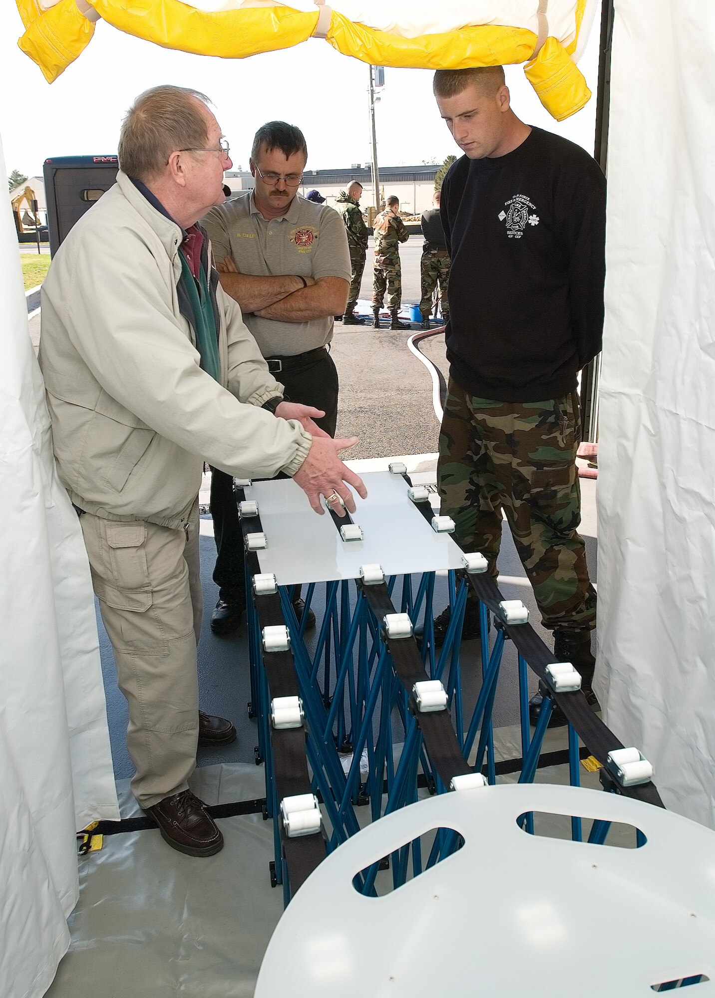 (Left to right) Jim Kolch, EAI Corporation counterterrorism with weapons of mass destruction subject matter expert assigned to the Installation Protection Program Lite, explains the procedures for decontaminating non-ambulatory people to Brian Cullen, 436th Civil Engineer Squadron Battalion chief of Special Operations, and Senior Airman Kyle O’Conner, 436th CES firefighter, during a training class Nov. 2 at Dover Air Force Base. (U.S. Air Force photo/Jason Minto)