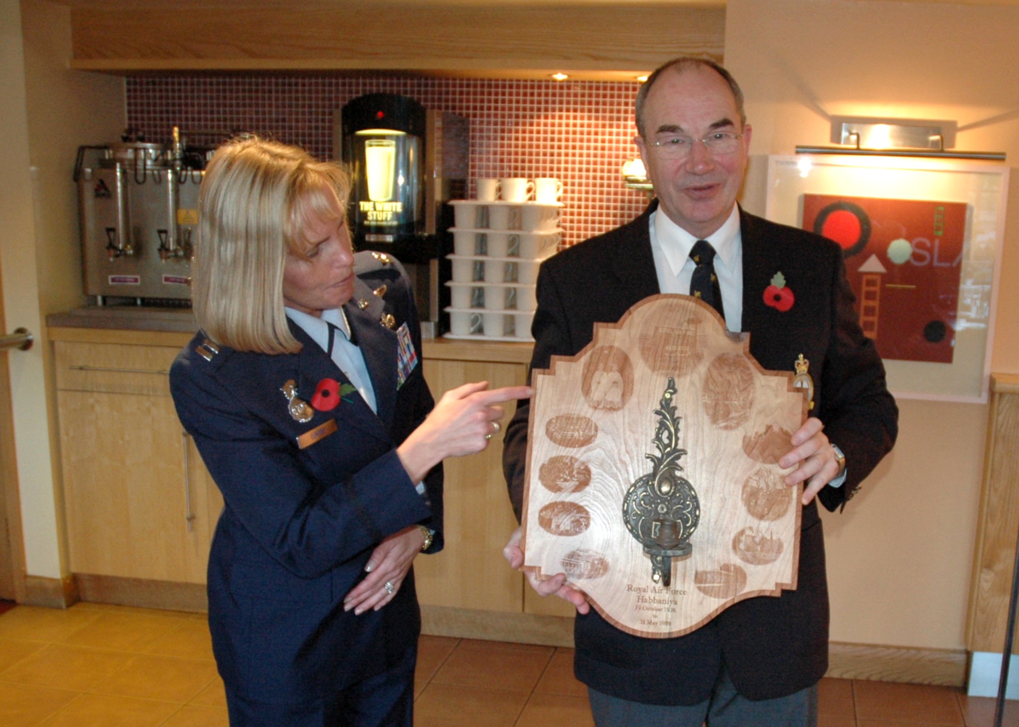 Capt. Jutta Cortes presents a plaque to Dr. Christopher Morris, honorary secretary of the RAF Habbaniya Association. The center of the plaque contains a candle sconce from the Officers Club at RAF Habbinaya, Iraq. (U.S. Air Force photo/Tech. Sgt. Scott Wakefield)
