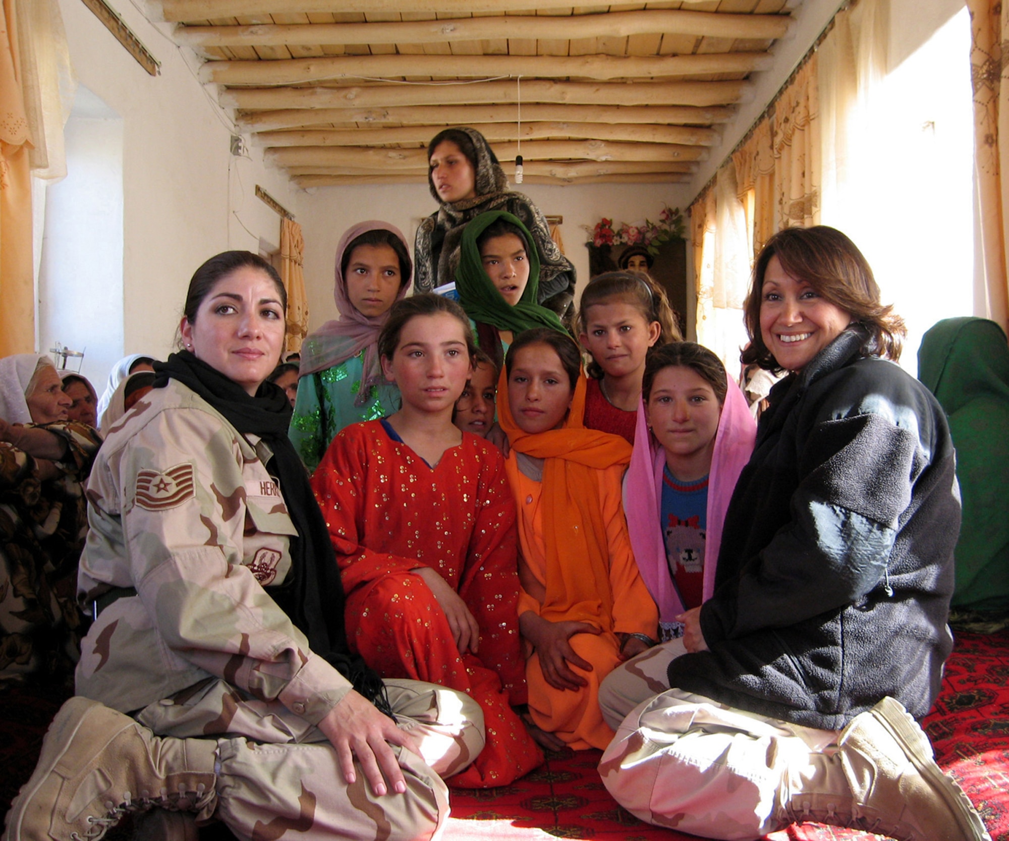 PANJSHIR PROVINCE, Afghanistan -- Women across the province meet here monthly with the female members of the Panjshir Provincial Reconstruction Team to learn from each other and exchange ideas. Affectionately known as  "Chick Chats," the cultural exchange was the brainchild of the U.S. Agency for International Development representative on the Panjshir PRT as an outreach for the Panjshiri women. Local Afghan female leaders organize and convene the meetings. Panjshir PRT members Tech. Sgt. Grace Herrera and Shahla Hammond pose with local girls at a meeting in Anaba District recently. (Courtesy photo\Amy Frumin)