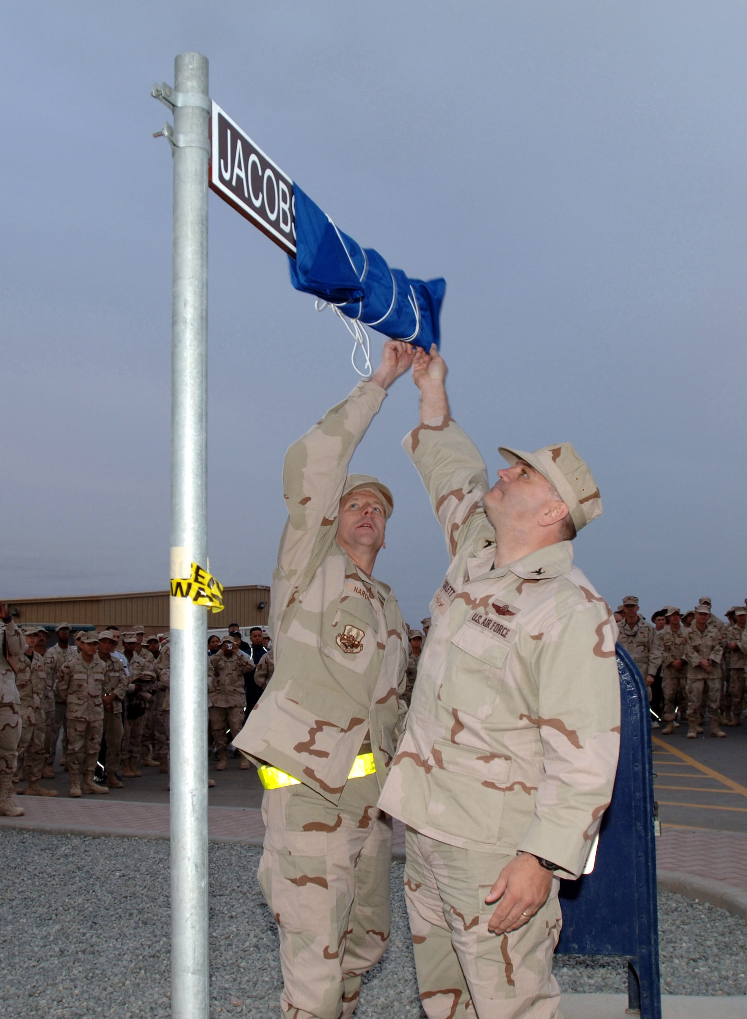 Chief Master Sgt. Thom Narofsky and Col. Paul Curlett dedicate a road as Jacobson Avenue at a deployed location in Southwest Asia Nov. 10. The street dedication was part of a memorial ceremony for all veterans, including Airman 1st Class Elizabeth Jacobson who was killed while on a convoy near Camp Bucca, Iraq. Her vehicle was hit by an improvised explosive device on Sept. 28, 2005. She was the first female Airman killed in the line of duty supporting Operation Iraqi Freedom. Colonel Curlett is the commander of the 386th Air Expeditionary Wing and Chief Narofsky is the command chief. (U.S. Air Force photo/Tech. Sgt. Andy Bellam)  