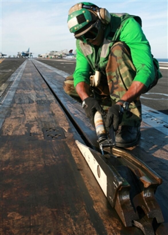 Airman Silas Shackelford, a U.S. Navy aviation boatswain's mate, greases a steam catapult shuttle prior to flight operations aboard the aircraft carrier USS John C. Stennis (CVN 74) as the ship operates in the Pacific Ocean on Nov. 10, 2006.  Stennis is serving as the flagship for Commander, Carrier Strike Group 3 in a joint task force exercise off the coast of southern California.  