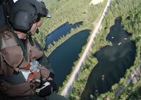 EIELSON AIR FORCE BASE, Alaska - Staff Sgt Dave Torrance of the 210th Rescue Squadron from Elmendorf AFB, Alaska looks down at the Lady of the Lake as they return from their exercise here on June 20, 2006. Lady of the Lake is the final resting place for a WB-29 Aircraft that crashed and was later towed to that lake for underwater extrication training. (U.S. Air Force Photo by Airman Jonathan Snyder)