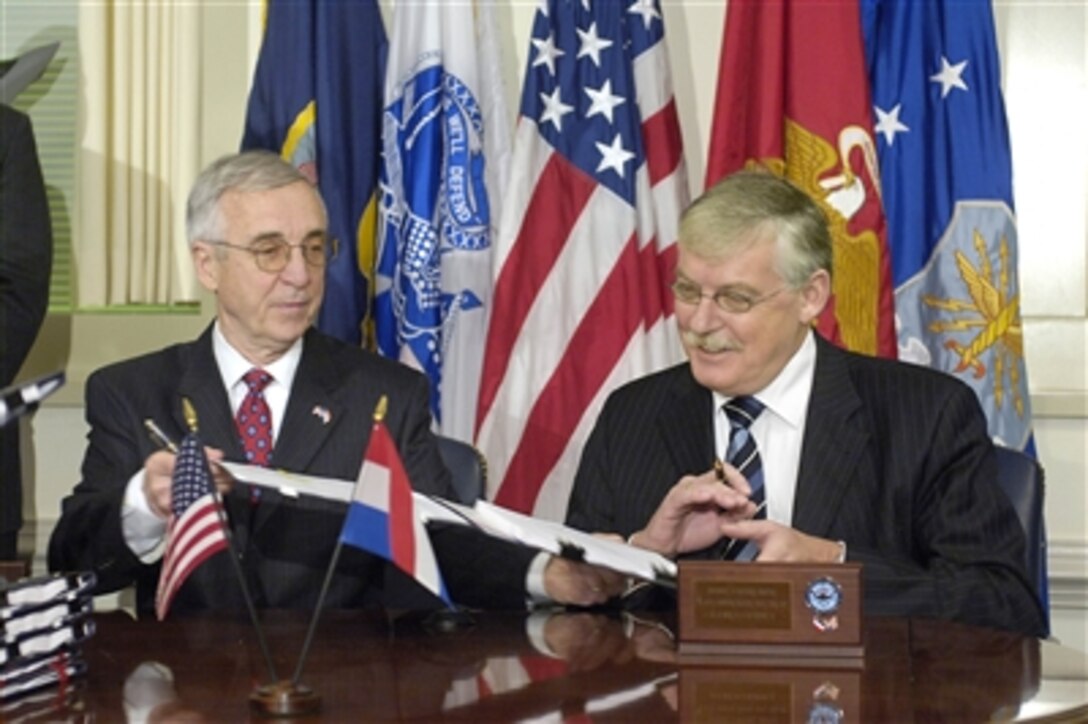 Deputy Secretary of Defense Gordon England (left) passes a Memorandum of Understanding on the Joint Strike Fighter program to Netherlands Deputy Secretary of Defense Cees van der Knaap (right) during a signing ceremony in the Pentagon on Nov. 14, 2006.  The memorandum concerns details of future cooperation in the production, sustainment, and follow-on development of the aircraft program.  The Joint Strike Fighter is the largest ever U.S. Department of Defense acquisition program.  