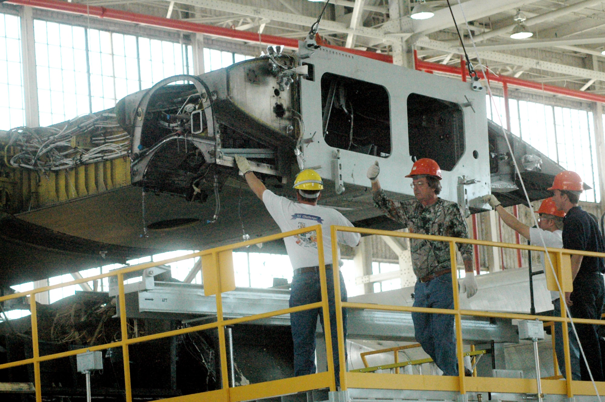 Workers guide the center wing box as it is lifted from a C-130 Hercules. A three-phase project is under way at Warner Robins Air Logistics Center, Robins Air Force Base, Ga., to replace the center wing boxes in all C-130 models except the C-130J.  (U.S. Air Force photo/Sue Sapp) 

