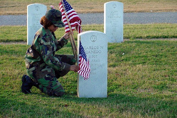 Master Sgt. Lisa Hill, NCO in charge of the 97th Logistics Readiness Squadron's Aerial Operations Flight, places a flag on the grave of a veteran at the Altus Cemetery Nov. 9.  Along with members of the Veterans of Foreign Wars Post 4876, more than 60 LRS troops showed up to honor 1600 veterans buried there.  (U.S. Air Force photo by Senior Airman Brian Engle)
