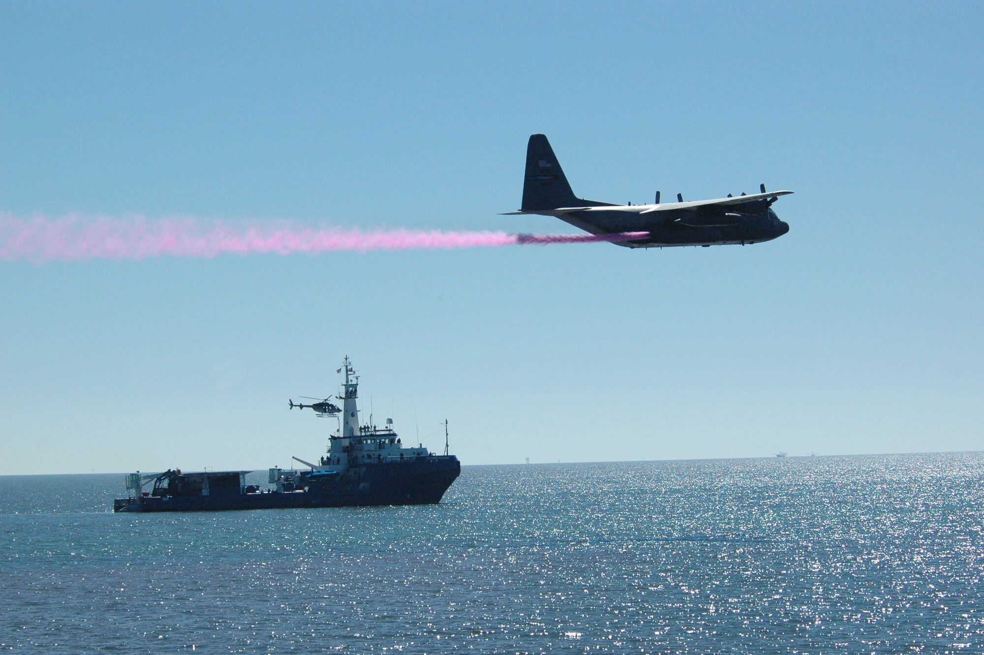 THE GULF OF MEXICO – As spectators and crew members on the deck of the Marine Spill Response Corporation’s Southern Responder enjoy their front row seats, a C-130 skims over a simulated oil slick marked by bright green dye.  The colored water being sprayed by the C-130 simulates an oil dispersant.  The C-130H is assigned to the Air Force Reserve Command’s 910th Airlift Wing, located at Youngstown Air Reserve Station, Ohio.  It was participating in an oil dispersant exercise being held six miles off the shore of Galveston, Texas, Nov. 8, 2006.