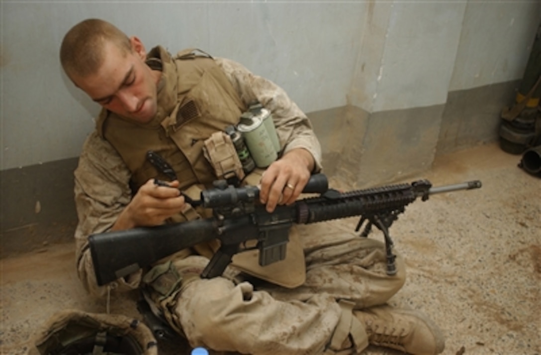 U.S. Marine Corps Lance Cpl. Thomas Echols uses some down time to clean his weapon as his fellow Marines establish a command post in Ramadi, Iraq, on Oct. 29, 2006.  Echols is attached to the 1st Battalion, 6th Marine Regiment.  