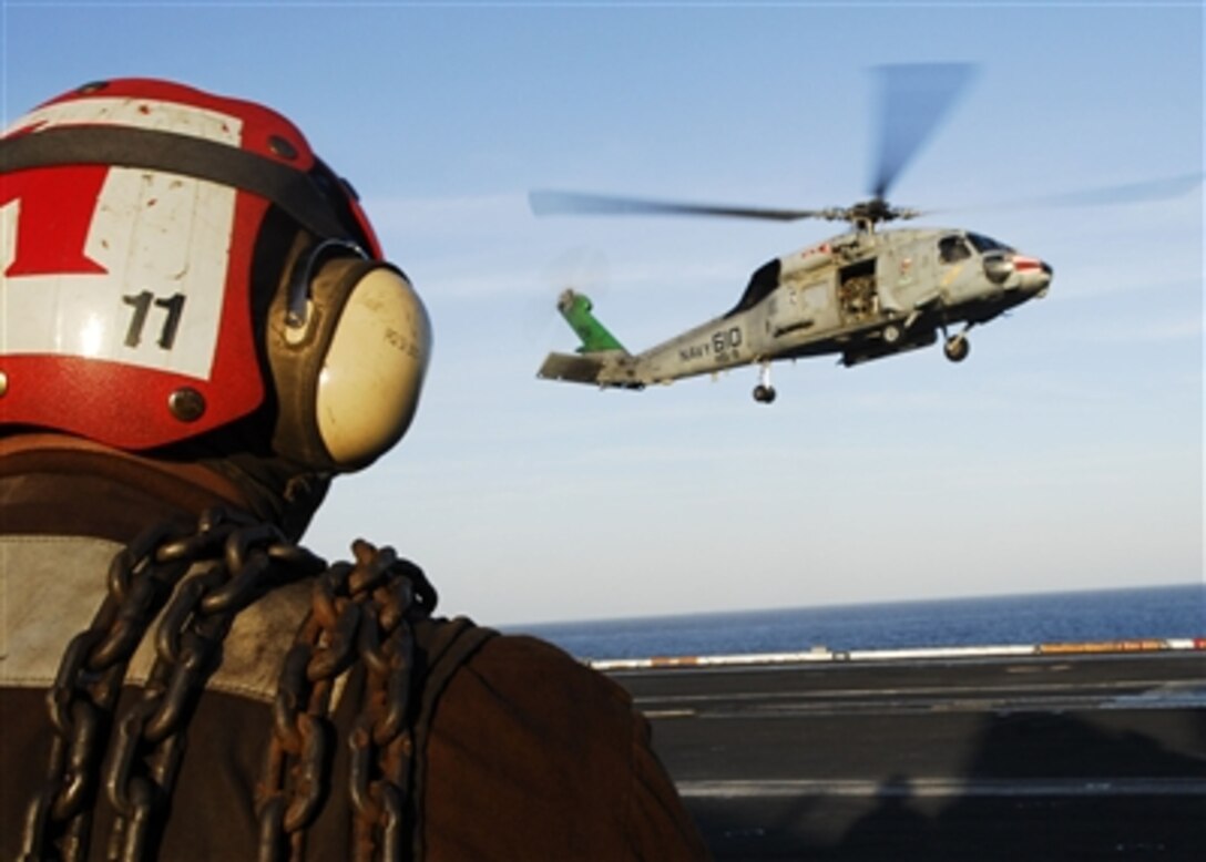 A U.S. Navy line division sailor stands ready with chock and chains to secure an SH-60F Seahawk helicopter as it lands on the USS John C. Stennis, Nov. 10, 2006.