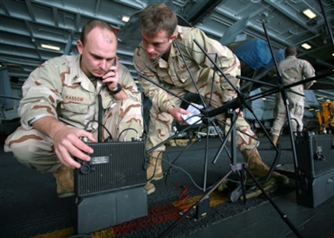Petty Officer 1st Class Ray Kassow (left) and Petty Officer 3rd Class Chris Eichas test a satellite communication system in the hangar deck of the aircraft carrier USS John C. Stennis (CVN 74) as the ship operates in the Pacific Ocean on Nov. 9, 2006.  Kassow and Eichas are Navy explosive ordnance disposal technicians.  Stennis is serving as the flagship for Commander, Carrier Strike Group 3 in a joint task force exercise off the coast of southern California.  