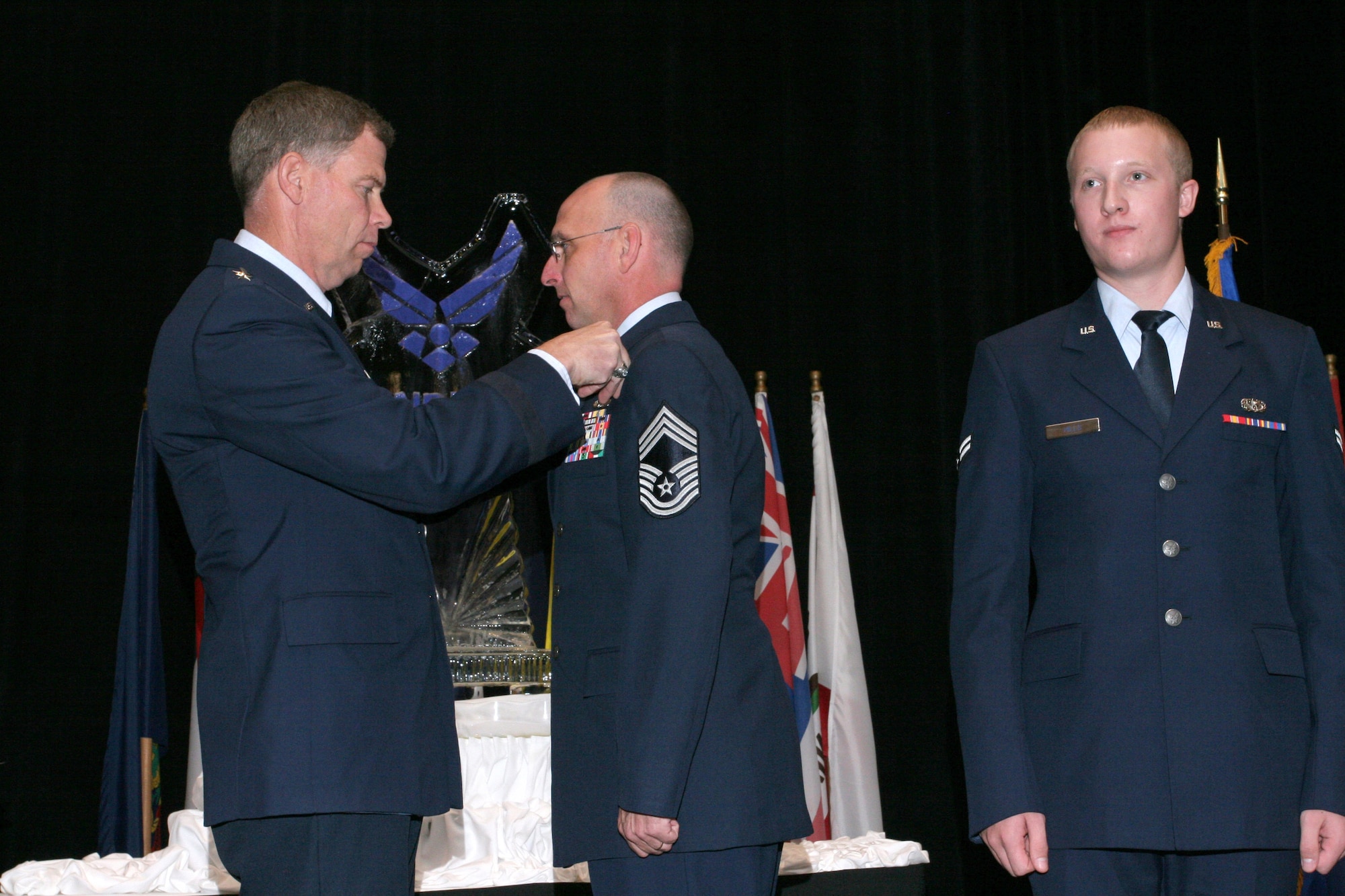 Maj. Gen. Del Eulberg, the Air Force civil engineer, pins the first civil engineer readiness occupational badge on Chief Master Sgt. Mike Connors during a ceremony at the Emergency Services Symposium in Dallas, while Airman 1st Class Adam Hills waits for his badge. Chief Connors is the senior-ranking enlisted member in the Air Force civil engineer readiness career field and Airman Hills is the most recent graduate of the civil engineer readiness course. (U.S. Air Force Photo/Linda Reineke)

