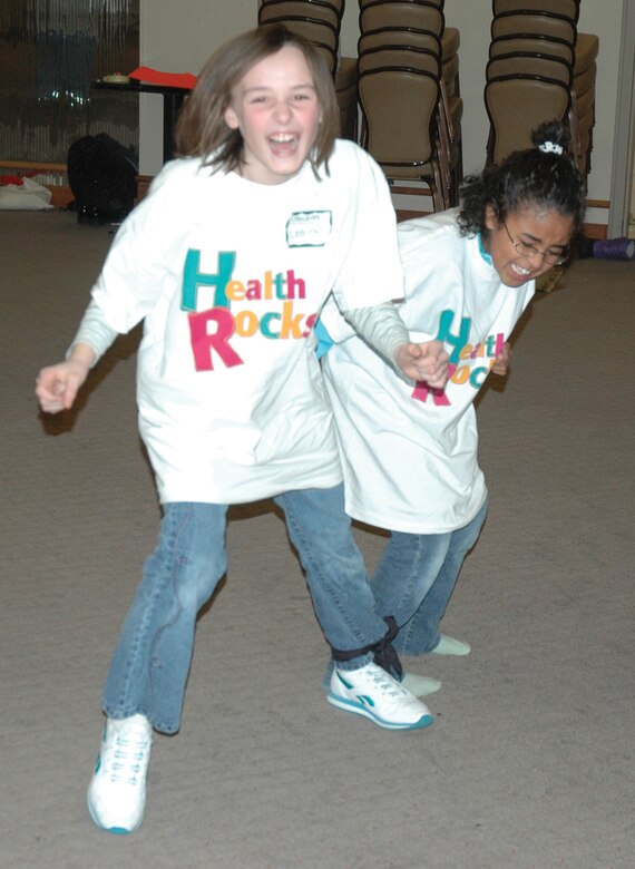 EIELSON AIR FORCE BASE, Alaska--The wingman culture involves the entire Iceman Team, Air Force active-duty, Guard, civilians and family members.  Leah Sauter, daughter of Tech. Sergeants Gennifer and Scott Sauter, and Aleah Appling, daughter of Karla and Senior Master Sgt. Robert Appling, act as each other's wingmen during Health Rocks! Nov. 10 at the Aurora Club. The girls are playing a game demonstrating how nicotine drags you down when trying to do day-to-day activities.