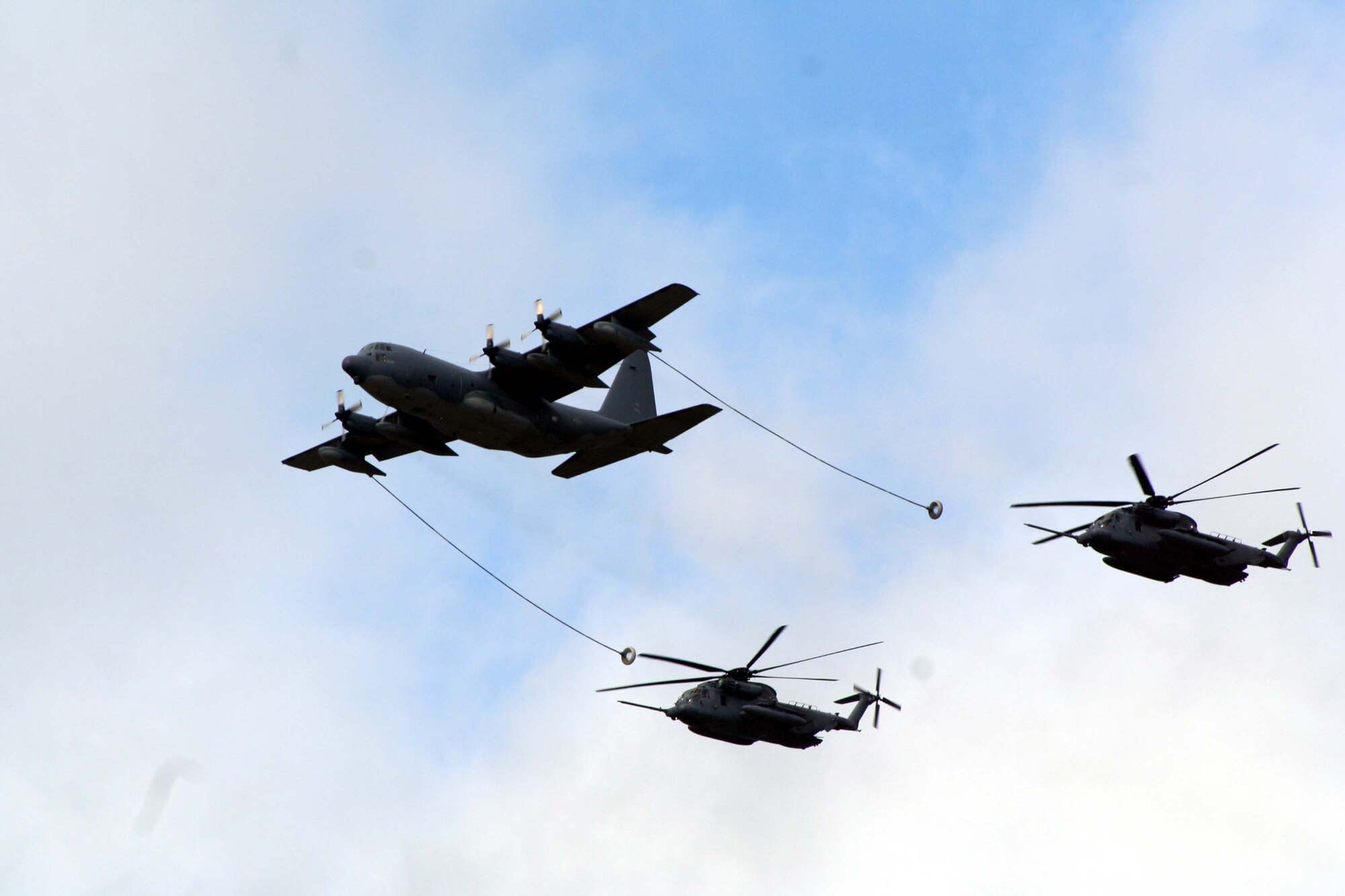 An MC-130P and two MH-53 PAVE LOWs fly over Hurlburt Field during a refueling mission at an air power demonstration.