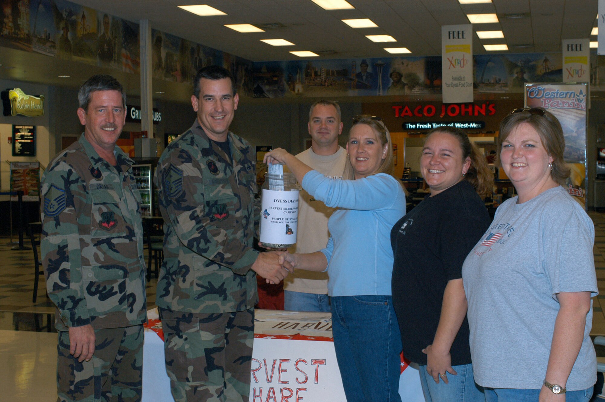 Dee Dee Orsak, Dyess' Enlisted Spouses Club president, and other ESC members hand a $500 check to Senior Master Sgt. Theodore Lambremont, 7th Aircraft Maintenance Squadron first sergeant, for the annual Warm Hearts Harvest Share funds drive Monday