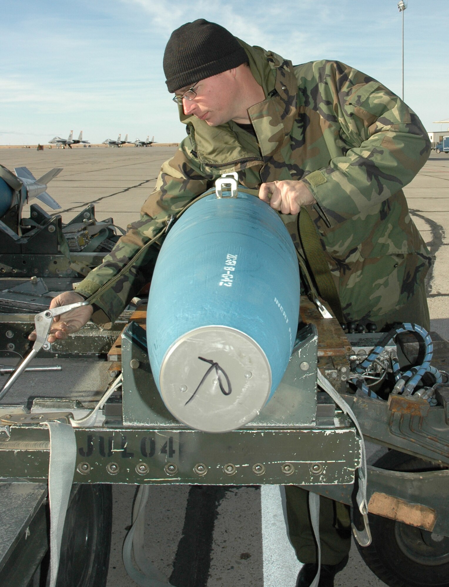 Staff Sgt. Timothy Dockens, 391st Aircraft Maintenance Unit weapons loader, straps down a BDU 50 practice bomb to a bomb loader as part of a scheduled weapons load Nov. 14. Recent upgrades to the squadron's fleet of fighters will allow the jets to carry a full array of satellite-guided weapons, including the Air Force's new small diameter bombs. Air Force photo by Master Sgt. Brian S. Orban